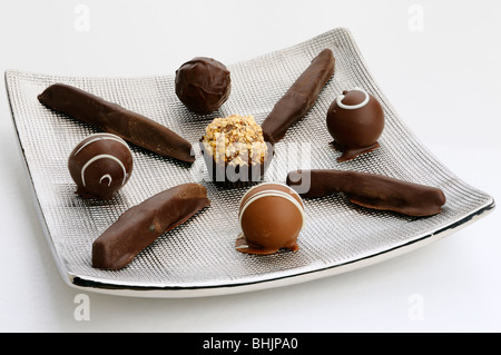 Truffes au chocolat fait main et de zeste d'orange confite sur une plaque d'argent sur fond blanc Banque D'Images