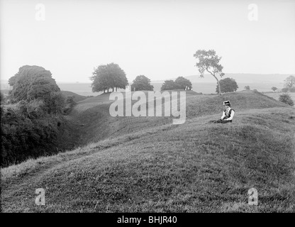 Une femme assise sur la banque extérieure à Avebury, dans le Wiltshire, 1908. Artiste : Harold St George Grey Banque D'Images