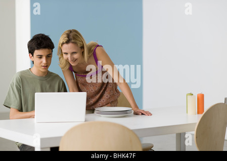 Teenage boy montrant mère laptop computer Banque D'Images