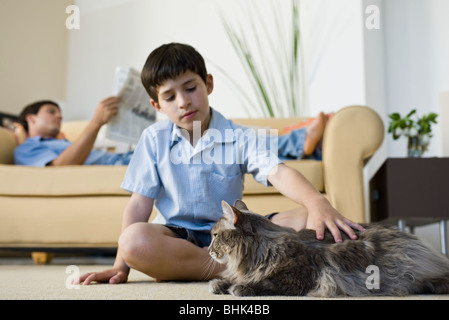 Jeune garçon assis dans le salon de chat pour enfants Banque D'Images