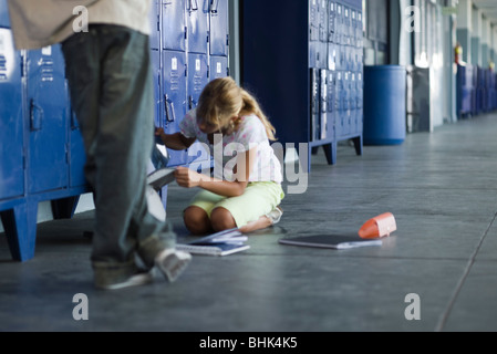 Junior High student picking up a chuté des fournitures scolaires, garçon debout en regardant Banque D'Images