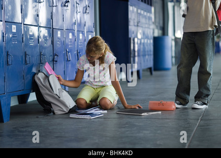 Junior High student picking up a chuté des fournitures scolaires, garçon debout en regardant Banque D'Images