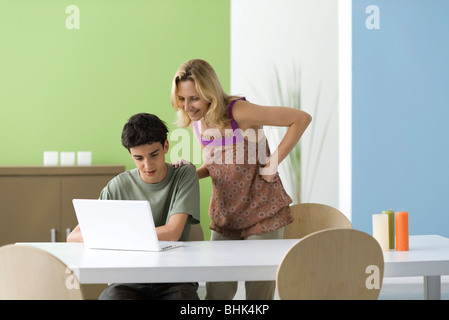 Teenage boy montrant mère laptop computer Banque D'Images