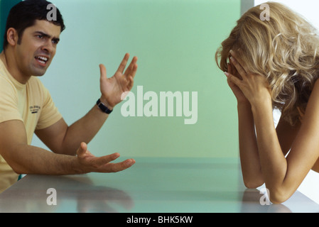 Couple arguing à table, woman holding head Banque D'Images