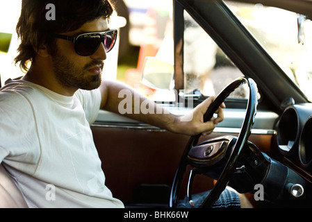 Jeune homme macho au volant Banque D'Images