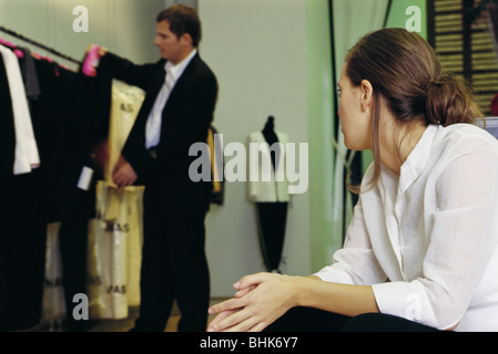 Jeune femme regardant l'homme à la recherche de vêtements en magasin Banque D'Images