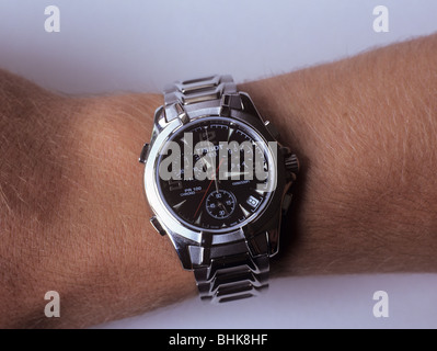 Un homme portant un Tissot montre-bracelet analogique avec bracelet en métal sur le bras droit. Banque D'Images