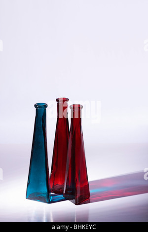 Rouge et bleu de vases en verre décoratif. Allumé à côté des réflexions colorées en fonte. Isolées. Copier l'espace. Banque D'Images