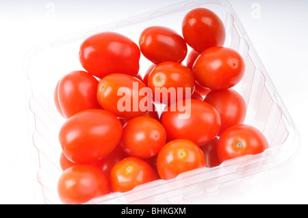 Tomates cerises rouges en contenant de plastique clair sur fond blanc Banque D'Images