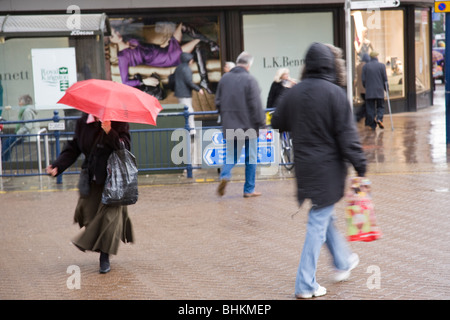 Les piétons traverser la route sous la pluie, à Kingston, Surrey, Angleterre. Banque D'Images