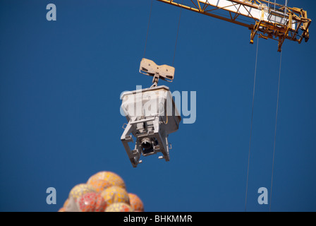 Une grue soulève un conteneur de ciment au-dessus de la pointe de l'un des tours de clad en céramique Anton la Sagrada Familia, la cathédrale. Banque D'Images