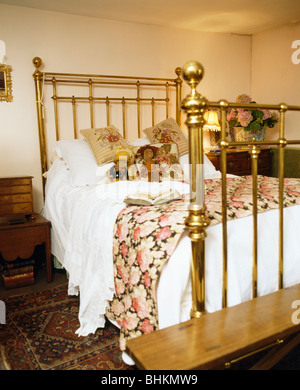 Courtepointe à motifs de roses et blanches sur des draps de lit en laiton antique chambre traditionnelle Banque D'Images