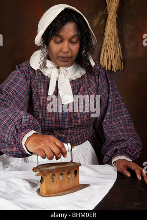 Scène de reconstitution d'une femme victorienne noire planche avec un ancien fer à repasser Banque D'Images