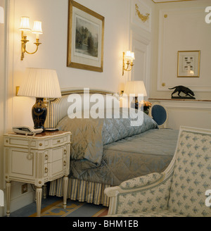 Les lampes allumées sur les tables de chevet de chaque côté du lit rembourré avec oreiller piqué gris et double-couverture en appartement chambres Banque D'Images