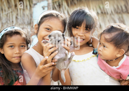 Village natal d'enfants tenant un chiot ; Darocotan ; Archipel Bacuit Island Palawan, Philippines ; Banque D'Images