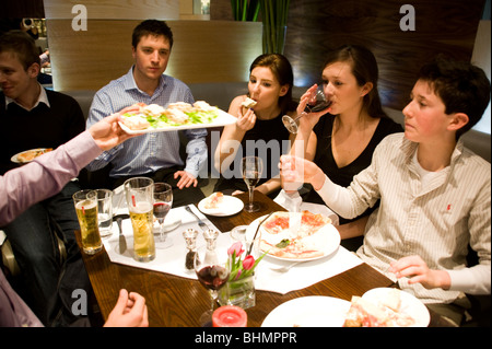 Un grand groupe de jeunes gens de manger dans un restaurant de pizza Banque D'Images