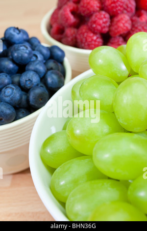 Bols de petit-déjeuner sain raisins, bleuets et framboises, l'accent est mis sur les raisins à l'avant-plan. Banque D'Images