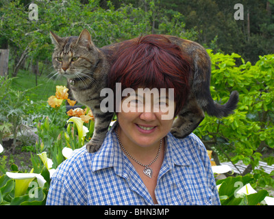 Femme eurasienne mature en bonne santé (chinoise / italienne) dans son jardin avec un chat de compagnie sur son épaule Banque D'Images