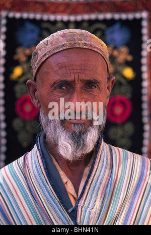 Homme ouzbèkes en costume traditionnel avec des tapis aux couleurs vives, Samarkand, Ouzbékistan Banque D'Images