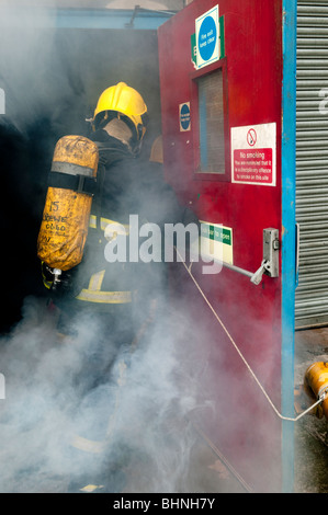 Pompier entre dans l'incendie de l'usine par le feu porte de sortie port BA Banque D'Images