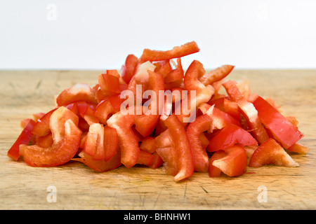 Close up de poivrons rouges hachés sur planche en bois sur un fond blanc. Banque D'Images