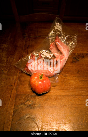 Encore une macabre slighty vie d'une grande peau de tomate steak et un lapin dans un sac sur une table de cuisine en bois Banque D'Images