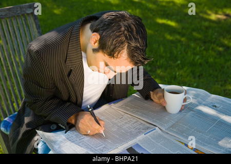 Jeune homme lisant le journal dans le jardin Banque D'Images