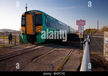 Un train de voyageurs passant sur moulin à marée de passage à niveau à commande manuelle dans le Sussex. Banque D'Images