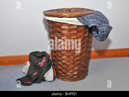 Un panier de blanchisserie avec un garçons vêtements sales pendaison hors de lui. Banque D'Images