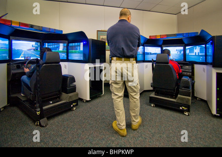 En tant qu'instructeur des montres, des agents de police pratique conduite à grande vitesse de compétences Compétences à l'auto-patrouille avec les simulateurs du vrai les volants. Banque D'Images