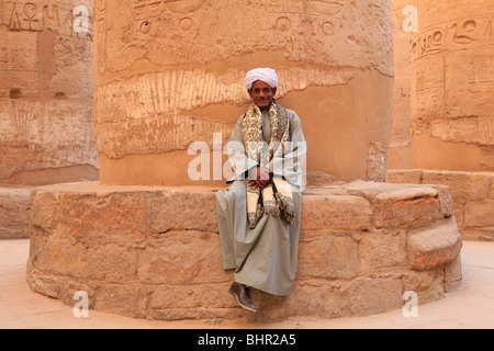 L'Homme égyptien en costume traditionnel assis dans la salle hypostyle du Temple de Karnak à Louxor, Egypte Banque D'Images