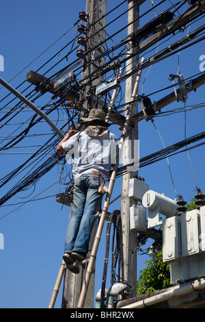 Électricien réparant l'alimentation électrique sur le câblage aérien; câblage domestique à Chiang Mai en Thaïlande, sans équipement ou équipement de protection. Banque D'Images