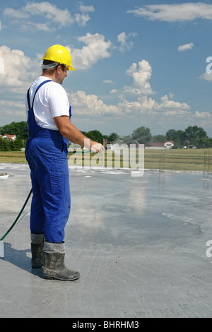Travailleur de la construction de béton frais d'arrosage à l'aide d'un flexible Banque D'Images