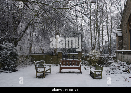 Des bancs dans le jardin du souvenir St Leonards Church recouvert de neige, Heston West London, UK Banque D'Images