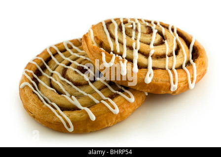 Deux tourbillons pâtisserie danoise de cannelle, avec du glaçage arrosé à travers eux, isolé sur un fond blanc. Banque D'Images