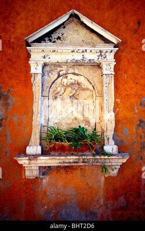 Vierge Marie la sculpture sur pierre avec des plantes sur le mur rouge/orange, Venise, Italie Banque D'Images
