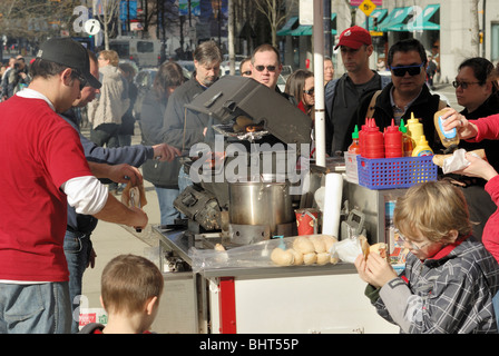 Beaucoup de gens faire la queue pour acheter un hot-dog à un vendeur de rue. Banque D'Images