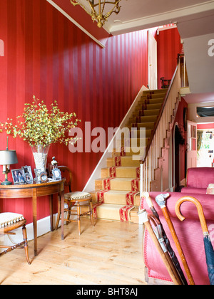 Papier peint à rayures rouge et parquet dans le hall avec plots rouge moquette crème on staircase Banque D'Images