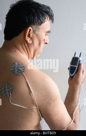 L'homme à l'aide d'une machine à double canal des dizaines pour le soulagement de douleur. Banque D'Images