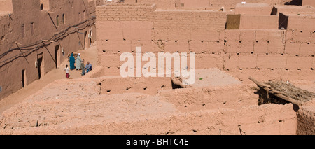 Une famille de marcher dans la boue et les bâtiments de brique adobe Mhamid el Ghizlane, dans le sud du Maroc Banque D'Images