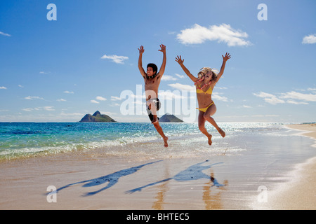 Jeune couple en sautant de joie sur une plage de Hawaï Banque D'Images