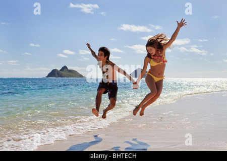 Jeune couple en sautant de joie sur une plage de Hawaï Banque D'Images