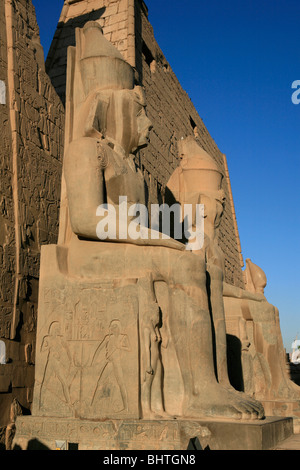 Vue de côté du premier pylône de deux statues de Ramsès le Grand à l'entrée principale du temple de Louxor à Louxor, Egypte Banque D'Images