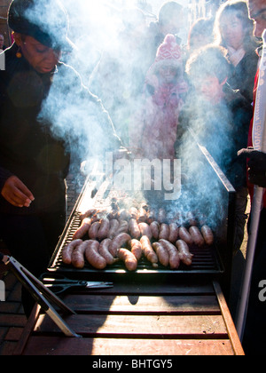 La cuisson des saucisses de porc femme primé au Farmer's Market à Stroud, Cotswolds, Gloucestershire, Royaume-Uni Banque D'Images