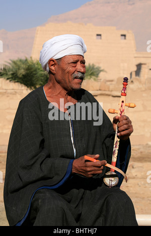 Fiddler traditionnel égyptien chanter tout en jouant le rebab à l'entrée du temple funéraire de Ramsès III Banque D'Images