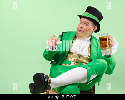 Lutin joyeux dans des vêtements verts tenant une pipe et une bière Banque D'Images