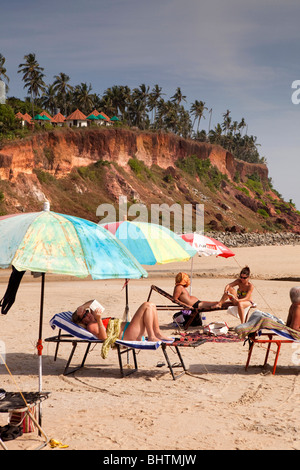 L'Inde, le Kerala, Varkala beach, les visiteurs occidentaux Bronzer sous des parasols colorés Banque D'Images