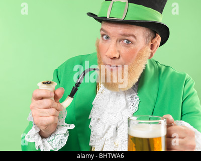 Lutin joyeux dans des vêtements verts tenant une pipe et une bière Banque D'Images