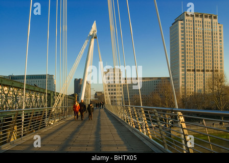 Les gens qui marchent le long de la Golden Jubilee Bridge dans le centre de Londres avec le Shell building en arrière-plan. Banque D'Images