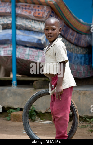 Garçon tenant une roue de bicyclette en Ouganda, Afrique Banque D'Images